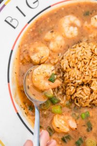 Jazz - A Louisiana Kitchen A bowl of shrimp gumbo with a serving of rice on the side, garnished with chopped green onions. A spoon is scooping up some shrimp and broth. Kansas City, Columbia