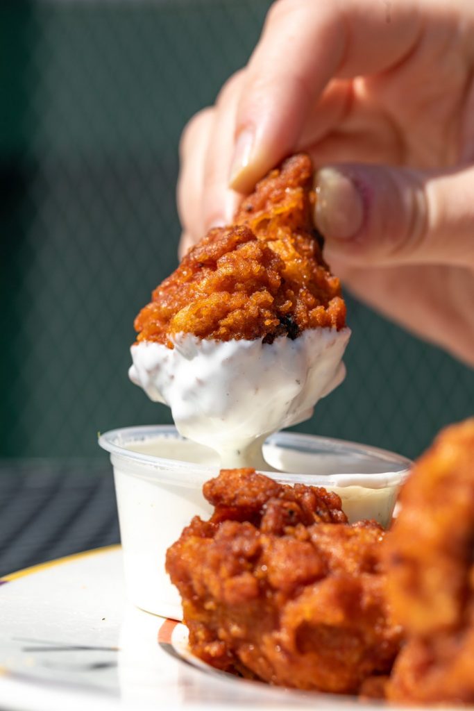 Jazz - A Louisiana Kitchen A hand dips a piece of fried chicken into a cup of creamy sauce. Kansas City, Columbia