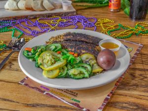 Jazz - A Louisiana Kitchen A plate of blackened fish with rice, steamed zucchini and squash, a boiled red potato, and a side of sauce. Mardi Gras beads are scattered on the table. Kansas City, Columbia