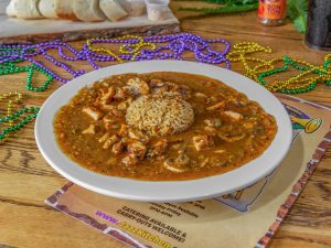 Jazz - A Louisiana Kitchen A plate of gumbo with rice on a wooden table, surrounded by Mardi Gras beads and a board with cheese and salami. Kansas City, Columbia