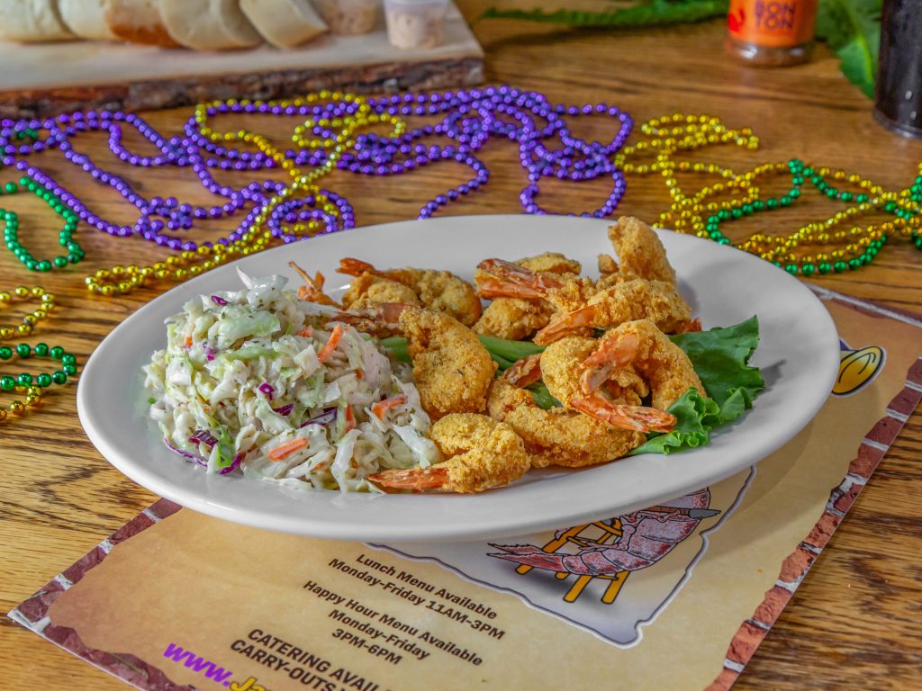 Jazz - A Louisiana Kitchen A plate of fried shrimp and coleslaw on a table with colorful beads and a menu underneath. Kansas City, Columbia