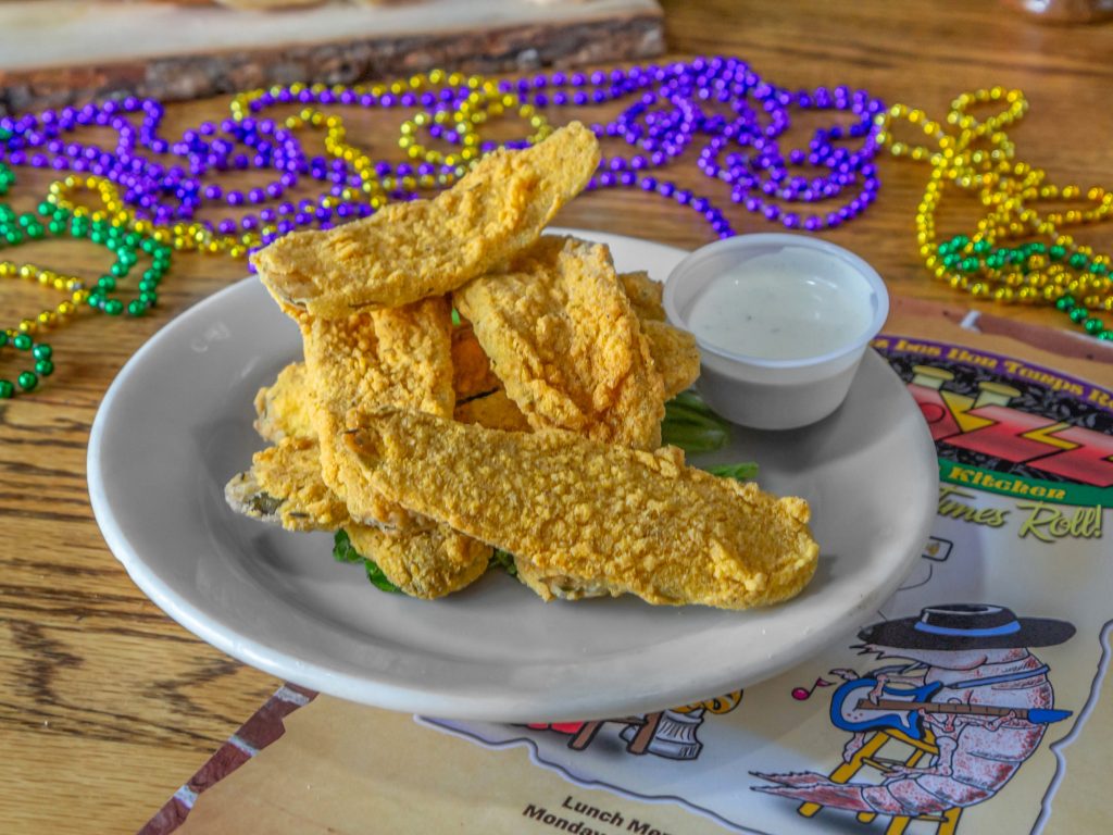 Jazz - A Louisiana Kitchen A plate of fried catfish strips with a small cup of dipping sauce, served on a table decorated with colorful Mardi Gras beads. Kansas City, Columbia