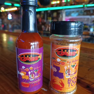 Jazz - A Louisiana Kitchen Two containers on a wooden table: a bottle labeled "Voodoo Juice" and a jar labeled "Bon Ton" with colorful graphics. Background features a bar with lights and decor. Kansas City, Columbia, cajun food restaurant near me
