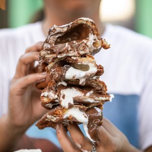Jazz - A Louisiana Kitchen A person holds a large stack of pastries filled with melted chocolate and marshmallow, with gooey filling oozing out. Kansas City, Columbia, cajun food restaurant near me
